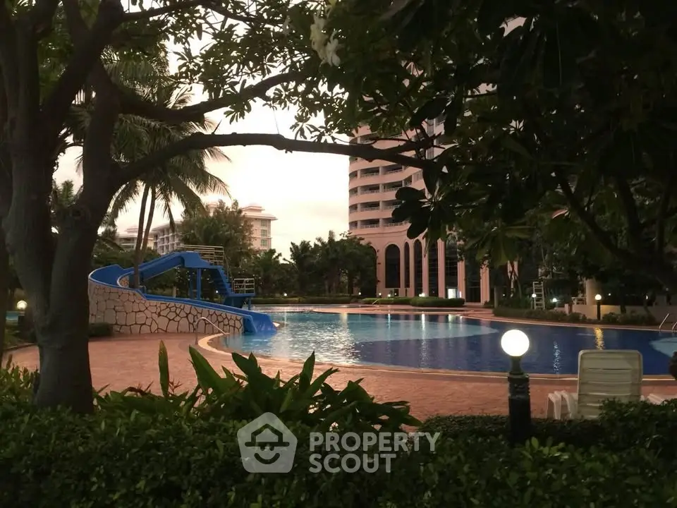 Luxurious residential pool area with slide and lush greenery