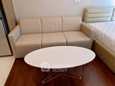 Modern studio apartment with cozy beige sofa and sleek white coffee table.