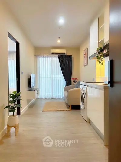 Modern living room with washing machine and cozy decor in open layout apartment.