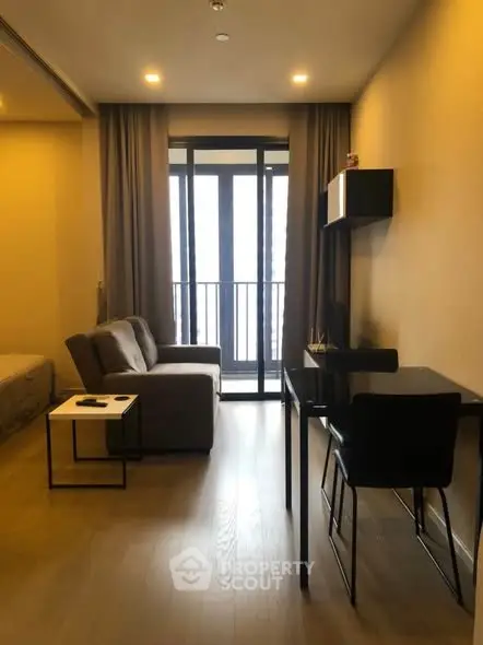 Modern living room with cozy sofa and work desk, featuring floor-to-ceiling windows and elegant decor.