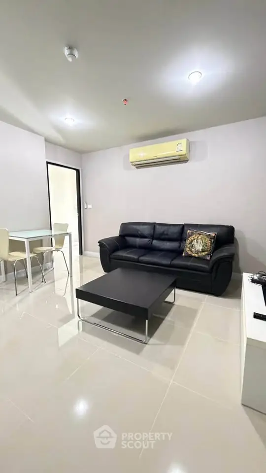 Modern living room with sleek black sofa and air conditioning, perfect for comfortable living.