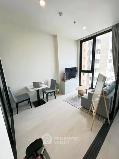 Modern living room with large windows and cozy seating area in a high-rise apartment.