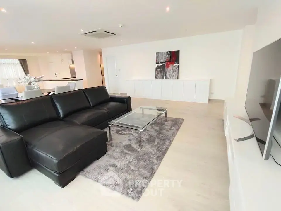 Spacious modern living room with sleek black leather sofa and stylish decor