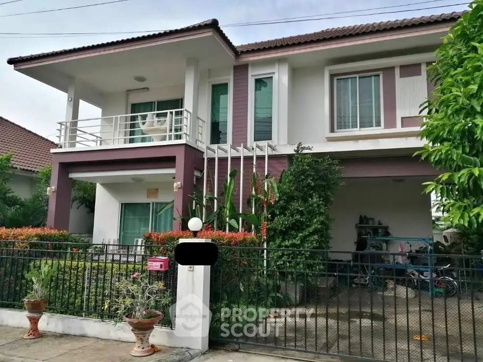 Charming two-story house with balcony and lush greenery in suburban neighborhood.