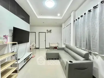 Modern living room with sleek gray sofa and large TV, perfect for relaxation and entertainment.