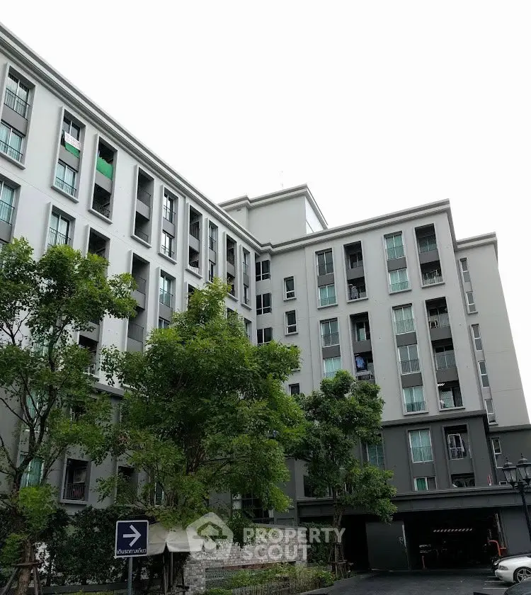 Modern apartment building exterior with lush greenery and multiple floors.