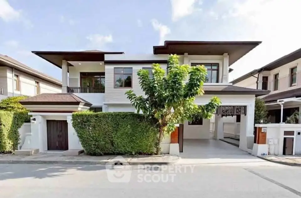 Modern two-story house with lush greenery and spacious driveway in a serene neighborhood.