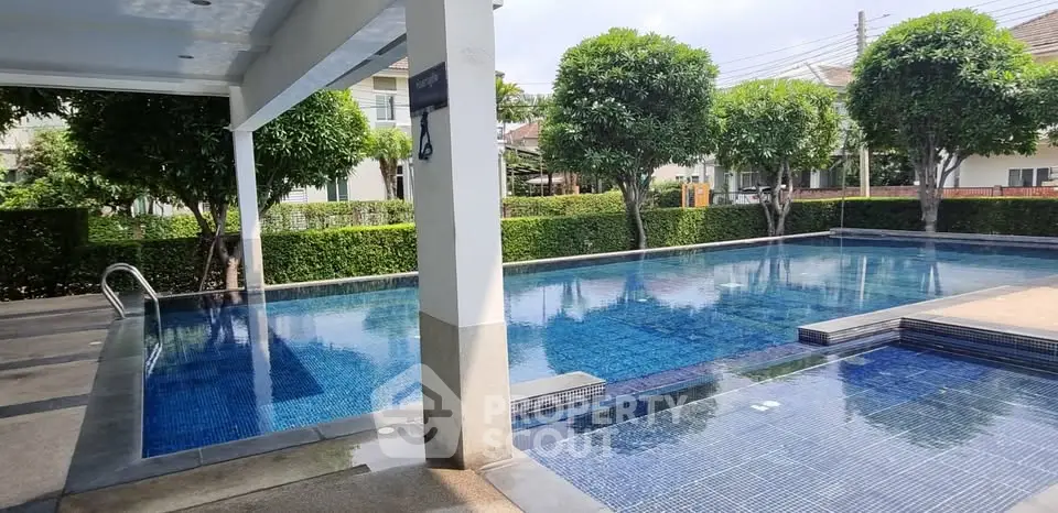 Luxurious residential pool area with lush greenery and modern design, perfect for relaxation and leisure.