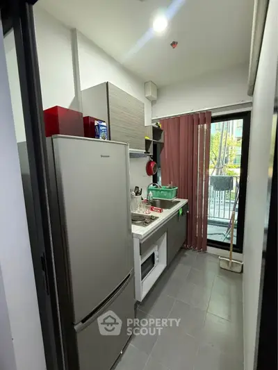 Compact kitchen with modern appliances and balcony view in urban apartment