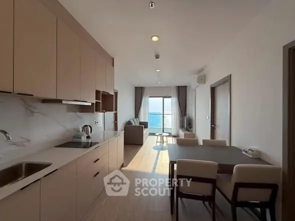Modern open-layout kitchen and living room with ocean view in luxury apartment.