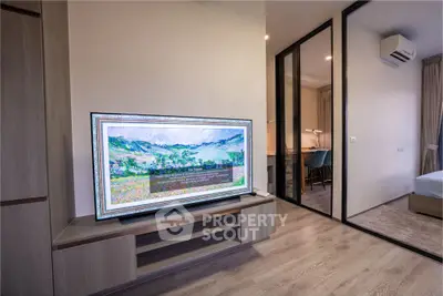 Modern living room with stylish TV setup and view into a cozy bedroom