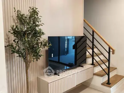Modern living room with stylish TV setup and elegant staircase