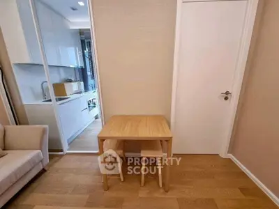 Cozy modern apartment with compact kitchen and dining area, featuring sleek design and warm wooden flooring.