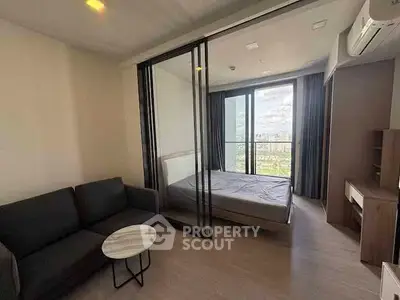 Modern studio apartment with glass partition and city view, featuring cozy living area and bedroom.