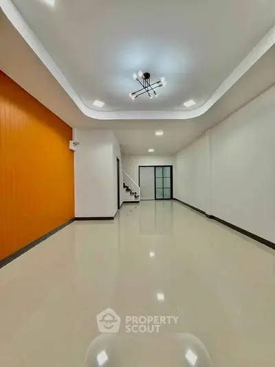 Spacious modern living room with sleek lighting and glossy floors.