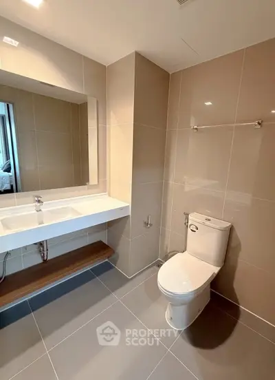 Modern bathroom with sleek fixtures and large mirror in contemporary apartment.