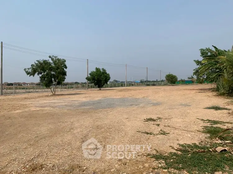 Expansive vacant land with potential for development, surrounded by trees and open sky.