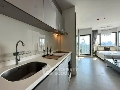 Modern open-layout kitchen with sleek design leading to a bright bedroom with city view.
