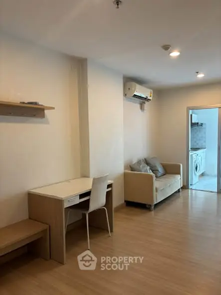 Modern living room with wooden flooring and compact furniture in a cozy apartment.