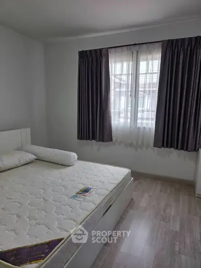 Cozy bedroom with large window and modern decor, perfect for relaxation and comfort.