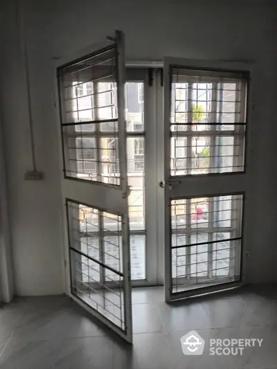 Modern apartment window with security bars and balcony view