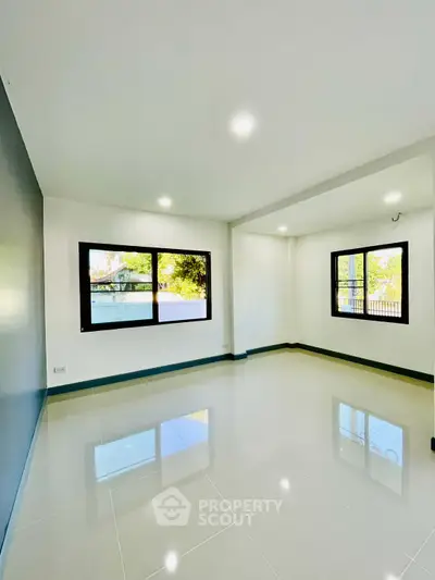 Spacious and bright living room with large windows and glossy tiled floors.