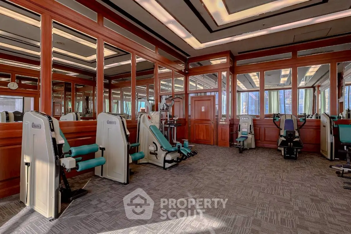 Luxurious gym with modern equipment and mirrored walls in upscale residential building.