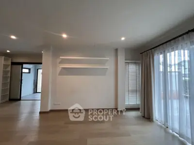 Spacious living room with wooden flooring and large windows for natural light.