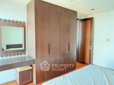 Spacious bedroom with elegant wooden wardrobe and vanity in modern apartment