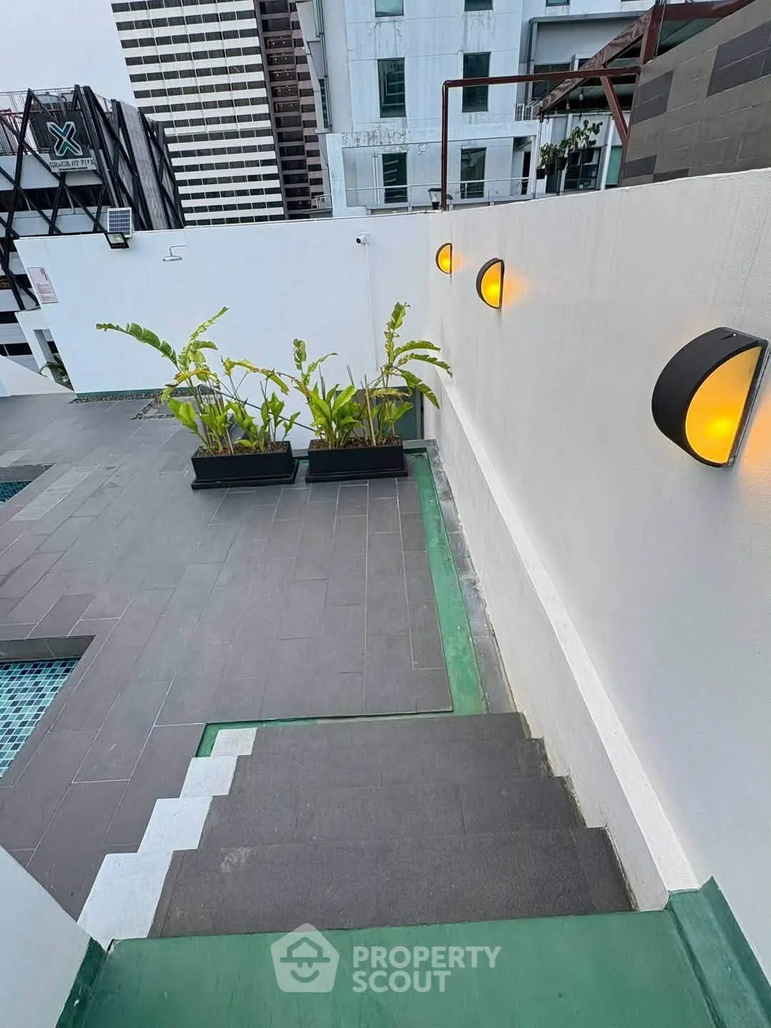 Modern rooftop area with stylish lighting and greenery, perfect for relaxation and city views.