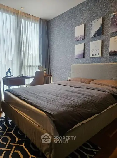 Modern bedroom with stylish decor and natural light, featuring a cozy bed and a sleek desk.