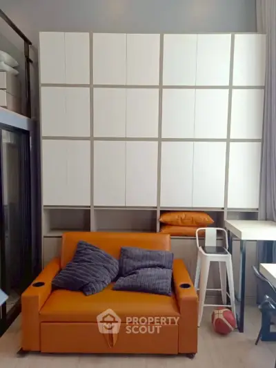 Modern living room with stylish orange sofa and floor-to-ceiling storage cabinets.