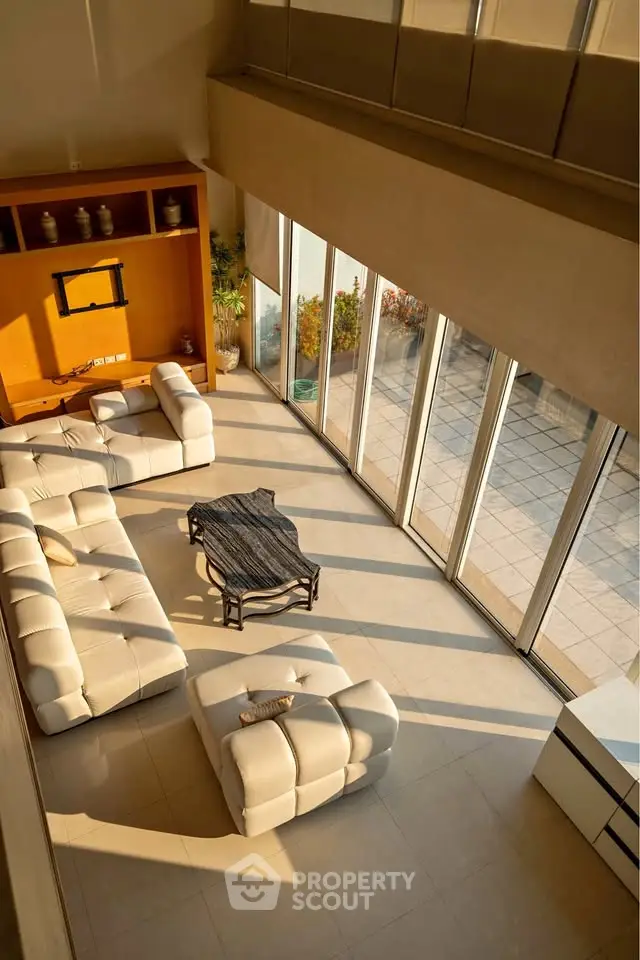 Luxurious living room with large windows and modern white sofas, offering abundant natural light and spaciousness.