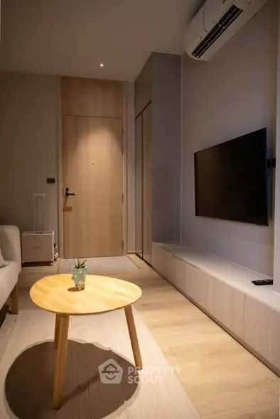 Modern living room with sleek furniture and wall-mounted TV in a cozy apartment.