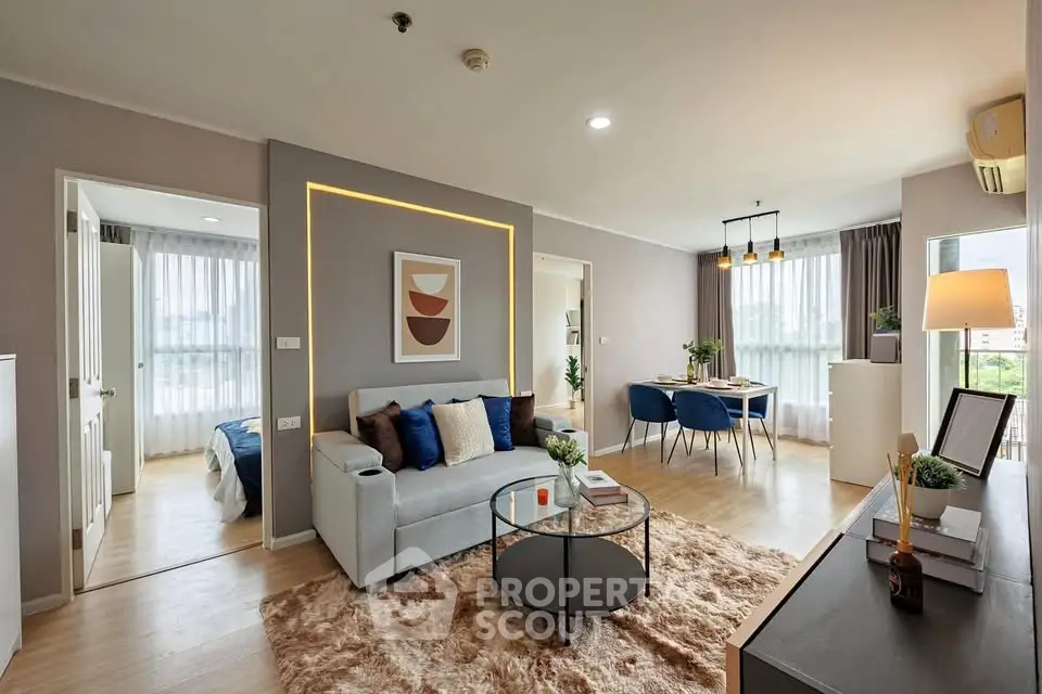 Modern living room with stylish decor and open dining area, featuring natural light and cozy ambiance.