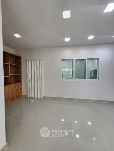 Spacious modern interior with sleek tile flooring and recessed lighting, perfect for versatile living space.