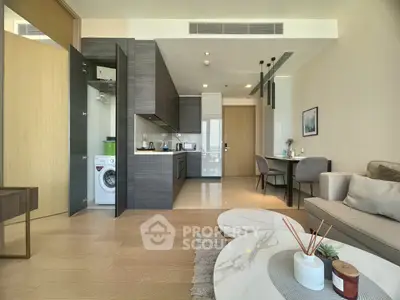 Modern open-plan living room with sleek kitchen and cozy dining area, featuring stylish decor and natural light.