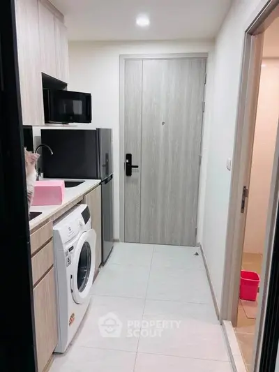 Modern compact kitchen with washing machine and microwave in sleek apartment