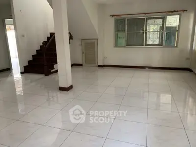 Spacious tiled living area with staircase and large window