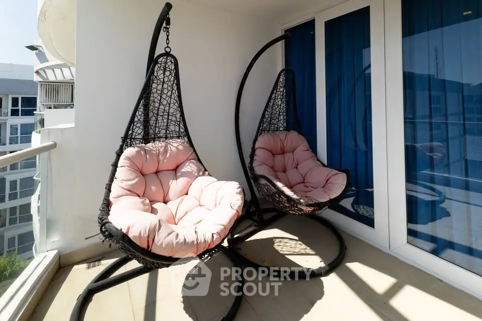 Charming balcony with cozy hanging chairs and modern glass doors in a stylish apartment.