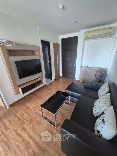 Modern living room with sleek furniture and wall-mounted TV in a cozy apartment setting.