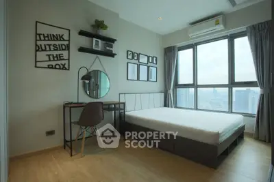 Modern bedroom with large window and stylish decor in urban apartment.