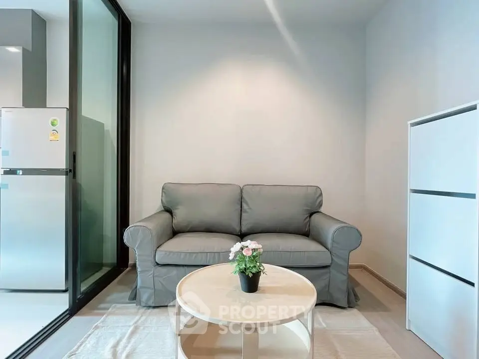 Cozy living room with modern sofa and round coffee table, adjacent to a sleek kitchen area.