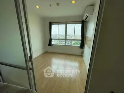 Spacious empty room with large window offering city views, perfect for customization.