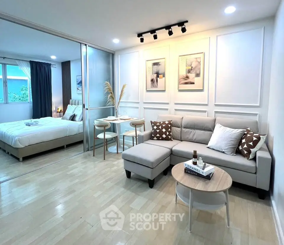 Modern living room with cozy sofa and elegant decor adjacent to a stylish bedroom.