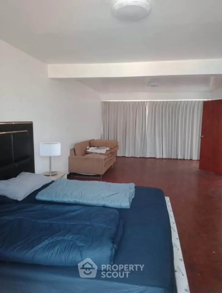 Spacious bedroom with modern decor and natural light, featuring a cozy bed and stylish sofa.