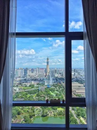 Stunning cityscape view from high-rise apartment window with lush greenery and skyline.