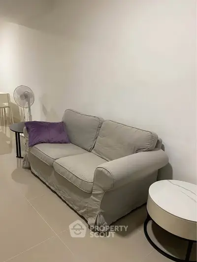 Cozy living room with a comfortable sofa and modern side table, perfect for relaxation.