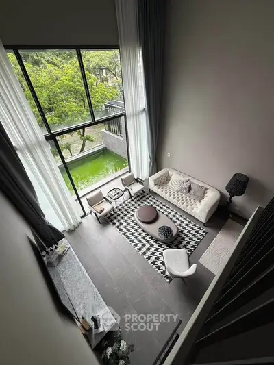 Stunning modern living room with high ceilings and large windows overlooking lush greenery.