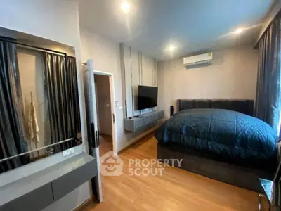 Modern bedroom with sleek design, featuring a wall-mounted TV and cozy bedding, perfect for relaxation.